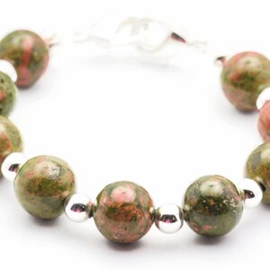 May include: A bracelet made with green and pink speckled beads and silver spacers.