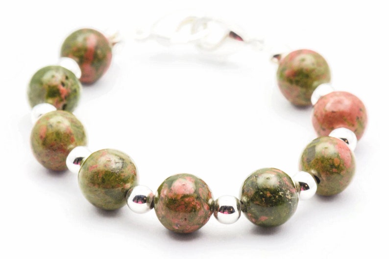 May include: A bracelet made with green and pink speckled beads and silver spacers.