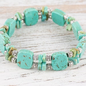 Op de afbeelding: Een turquoise en zilveren armband met vierkante turquoise kralen en zilveren spacer kralen.