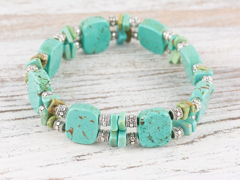 Op de afbeelding: Een turquoise en zilveren armband met vierkante turquoise kralen en zilveren spacer kralen.