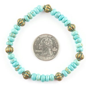 May include: A turquoise and gold beaded bracelet with a diameter of approximately 6.5 cm. The bracelet is made of small, round turquoise beads with a speckled pattern and gold-toned metal beads with a raised design.