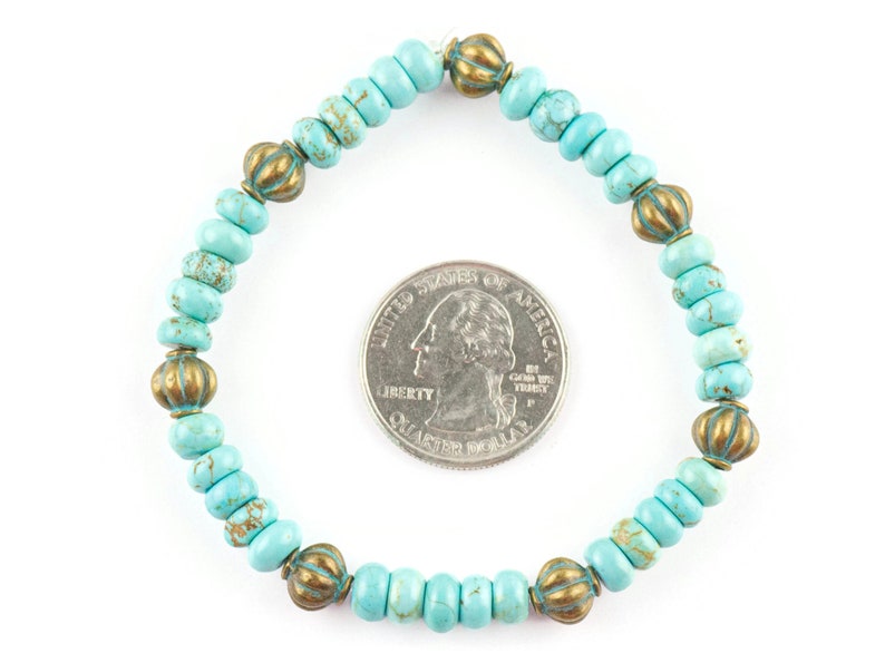May include: A turquoise and gold beaded bracelet with a diameter of approximately 6.5 cm. The bracelet is made of small, round turquoise beads with a speckled pattern and gold-toned metal beads with a raised design.