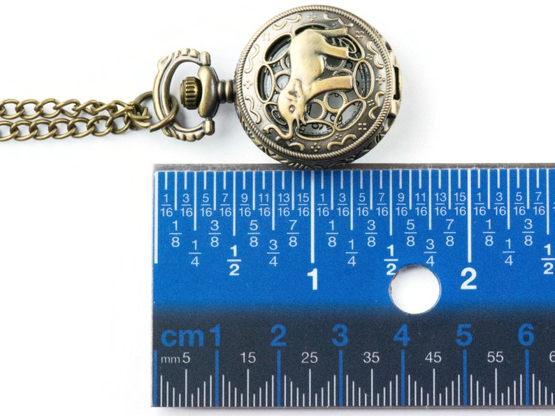 May include: A bronze pocket watch with an elephant design on the face. The watch is 2.5 cm in diameter and has a chain attached.