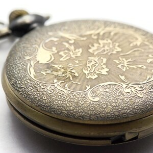 May include: A vintage gold pocket watch with an intricate floral design engraved on the front. The watch has a hinged lid and a chain attached.