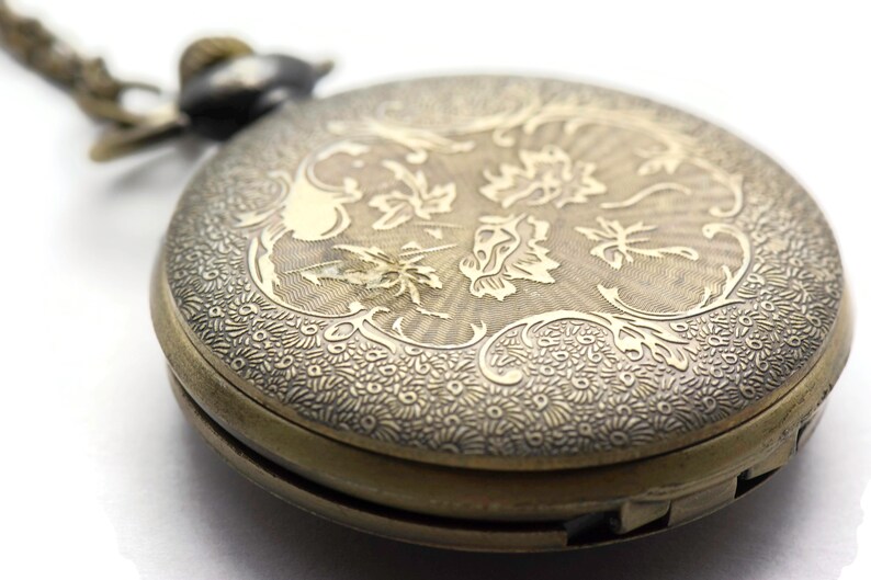May include: A vintage gold pocket watch with an intricate floral design engraved on the front. The watch has a hinged lid and a chain attached.