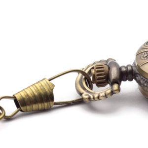 Pode incluir: Um rel&oacute;gio de bolso dourado com um design ornamentado e uma corrente anexada.