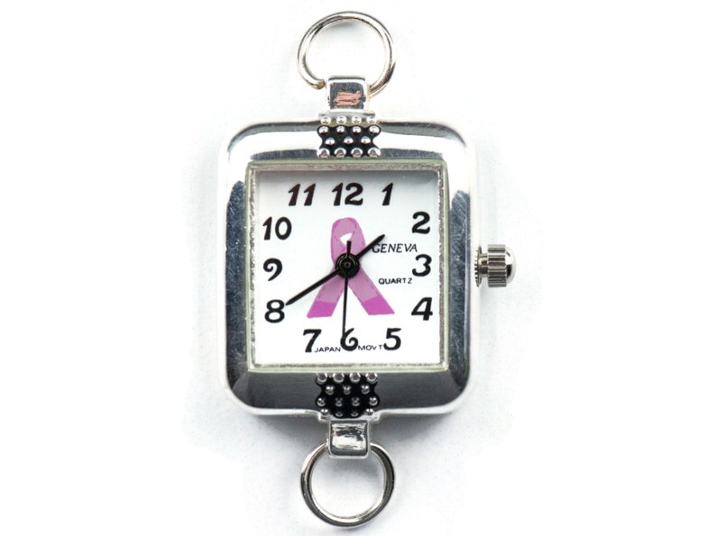 Pu&ograve; includere: Orologio quadrato color argento con quadrante bianco con numeri neri e un nastro rosa. L'orologio ha anelli nella parte superiore e inferiore per il fissaggio. Il quadrante dell'orologio recita "GENEVA QUARTZ" e "JAPAN MOV'T".