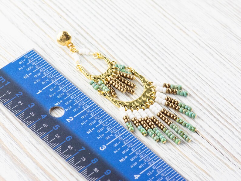May include: Gold and turquoise beaded dangle earrings with a hammered metal hoop. The earrings are approximately 3 inches long.