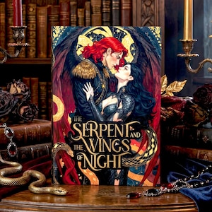 Puede incluir: Un libro titulado "The Serpent and the Wings of Night" con una ilustración romántica de dos figuras abrazándose. La imagen está ambientada en una biblioteca con velas y elementos decorativos.