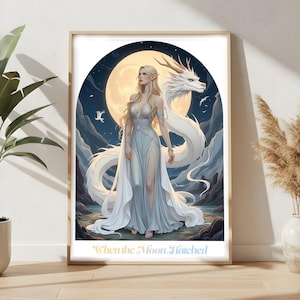 May include: A framed art print featuring a fantasy scene. A woman with long blonde hair and a flowing gown stands with a white dragon against a backdrop of a full moon and mountains. The text "When the Moon Hatched" is at the bottom.