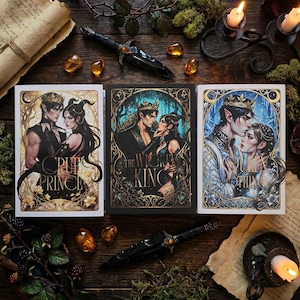 May include: Three fantasy book covers with illustrations of a man and woman, with the titles "The Cruel Prince", "The Wicked King", and "The Queen of Nothing". A black dagger and amber-colored stones are arranged around the books on a wooden surface.