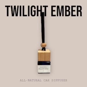 May include: A wooden car diffuser with a black string hanging from it. The diffuser is labeled "TWILIGHT EMBER" and is described as "ALL-NATURAL CAR DIFFUSER".