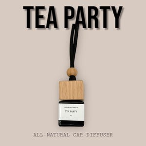 May include: A car air freshener with a black cord, wooden bead, and a wooden block top. The black glass bottle has a white label with the words "TEA PARTY" and "ALL-NATURAL CAR DIFFUSER".
