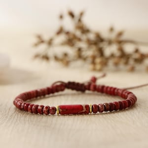 Könnte beinhalten: Ein rotes Perlenarmband mit goldener Verzierung und einem roten Steinanhänger.