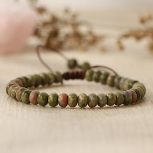 Peut inclure: Un bracelet en perles vertes et brunes avec une fermeture en cordon de cuir brun.