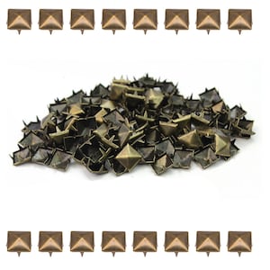 Può includere: Una collezione di borchie a forma di piramide color bronzo con punte. Le borchie sono disposte in file e un mucchio, ideali per aggiungere un elemento decorativo a vestiti, accessori o progetti artigianali.