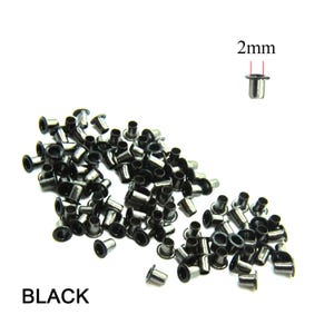 Könnte beinhalten: Ein Haufen schwarzer Metallstifte, jeder mit einem Durchmesser von 2 mm. Die Stifte werden zum Befestigen von Stoff oder Leder an anderen Materialien verwendet.