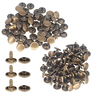 May include: A collection of antique brass-coloured metal rivets and caps. The set includes numerous circular, smooth-topped fasteners and matching cylindrical posts, arranged in two main clusters with three individual pairs displayed separately.