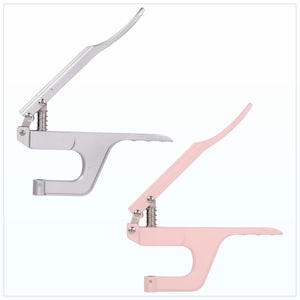 May include: Two metal rivet setters are shown, one silver and one pink. Each tool has a lever handle, a spring, and a curved arm. The silver tool is on the left, and the pink tool is on the right. The background is white.