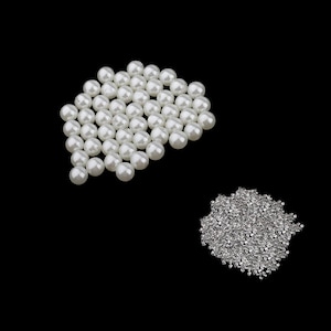 May include: A large quantity of white pearl beads and a pile of silver metal beads.
