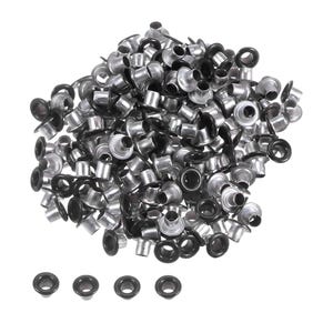 Può includere: Una grande collezione di piccoli occhielli in metallo con finitura argentata e bordo circolare nero. Gli occhielli sono disposti in un mucchio sparso, con quattro occhielli singoli posizionati in una fila orizzontale nella parte inferiore.
