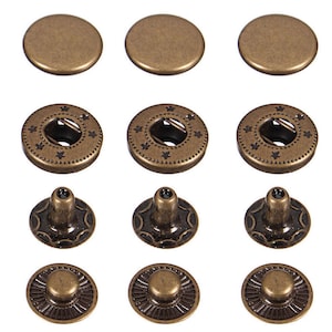 May include: A set of 10 antique gold metal snap fasteners. The set includes 3 pairs of round snaps, 2 pairs of round snaps with a decorative design, and 2 pairs of round snaps with a decorative design and a raised centre.