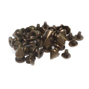 May include: A pile of antique gold-toned metal cone-shaped studs with screw backs.