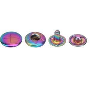 Può includere: Un set di quattro bottoni a pressione in metallo arcobaleno. I bottoni a pressione sono di forme e dimensioni diverse e sono tutti in metallo lucido.