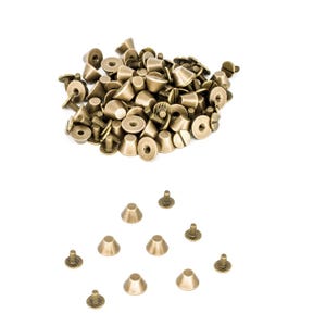 Könnte beinhalten: Ein Haufen goldfarbener, kegelförmiger Metallnieten mit flachem Boden und schraubenförmigem Kopf. Auf einem weißen Hintergrund sind 10 einzelne Nieten in Dreiecksform angeordnet.