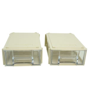 May include: Two beige plastic storage drawers with clear plastic fronts. The drawers are rectangular with a slightly textured surface and are designed to stack. The clear fronts allow for easy viewing of the contents.