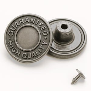 May include: Two round, metallic silver-toned denim buttons with a brushed finish. The front button features the embossed text "GUARANTEED" and "HIGH QUALITY" along the circular rim. A separate, small, pointed metal tack fastener is positioned below.