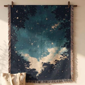 May include: A rectangular woven wall tapestry featuring a dark blue night sky with stars and clouds framed by dark tree silhouettes. Below, a cream-colored canvas tote bag with star graphics, a tan fedora hat, and a small potted succulent plant.
