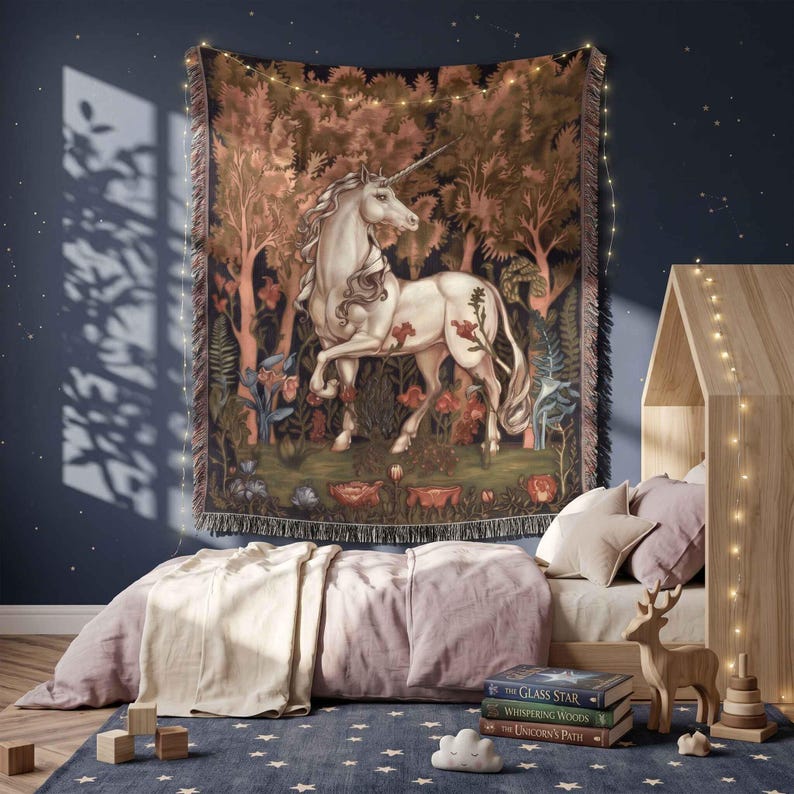 May include: A woven wall tapestry featuring a white unicorn standing in a dense forest with dark foliage and red flowers. The rectangular textile has a fringed edge and displays a detailed scene of the mythical creature amidst trees and plants.