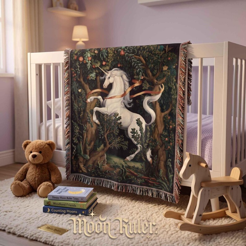 May include: A woven throw blanket featuring a white unicorn in a dark forest setting with fruit-laden trees and a flowing ribbon. The blanket has a fringed edge and is draped over a white crib. The text Moon Ruler is visible at the bottom.