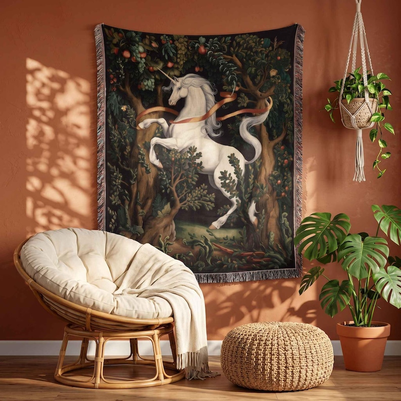 May include: A rectangular woven wall tapestry featuring a white unicorn standing in a dark, lush forest filled with trees, foliage, and fruit. The unicorn is depicted with a long, flowing mane and tail, surrounded by a light-colored ribbon element.