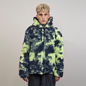 Può includere: Una giacca in pile mimetica blu e verde con chiusura a zip e cappuccio.