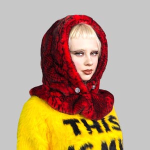 May include: A woman wearing a red faux fur hooded scarf with a yellow faux fur jacket that says "This is my" on the front.