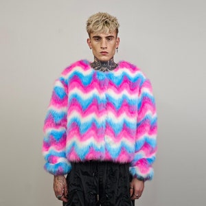 May include: A pink, blue and white faux fur jacket with a chevron pattern. The jacket has a zip closure and long sleeves.