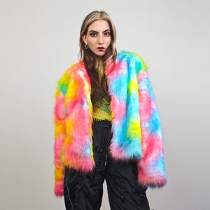 Può includere: Una giacca in pelliccia sintetica tie-dye arcobaleno con un design a maniche lunghe. La giacca è rosa, blu, gialla e bianca.