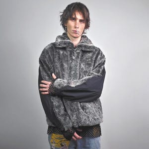 May include: A gray faux fur jacket with a snakeskin pattern, black sleeves, and a collar. The jacket has a zipper closure and is worn with ripped jeans. The sleeves have a mesh detail.