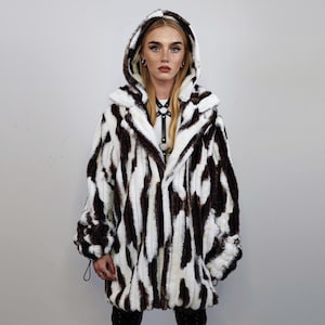 May include: A white and brown zebra-print faux fur hooded jacket with a zipper closure.