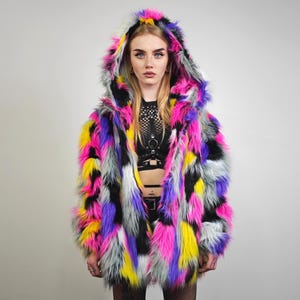 Può includere: Un cappotto in finta pelliccia con cappuccio dai colori vivaci, con un design patchwork in rosa, giallo, viola, nero e grigio. Il cappotto ha una vestibilità ampia e un grande cappuccio, creando un capo audace.