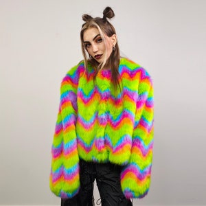 May include: A colourful faux fur jacket with a chevron pattern in shades of pink, green, blue, and orange. The jacket has a zip closure and long sleeves.