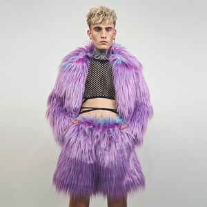 Könnte beinhalten: Eine Person trägt eine leuchtend lila Kunstfelljacke und passende Shorts. Die Jacke und Shorts haben eine lange, zottelige Textur mit Akzenten in Blau und Rosa. Dazu ein schwarzes Mesh-Top.