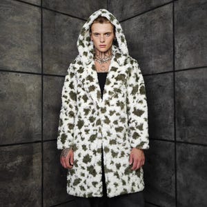 May include: A long, hooded coat with a white base and olive green spots. The coat is open in the front and has a soft, textured appearance. The hood is up, and the coat appears to be made of a faux fur material.