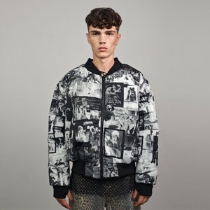 May include: A black and white patterned bomber jacket with a zipper closure. The jacket has a variety of images and text printed on it, including "Trans Power" and "Out".