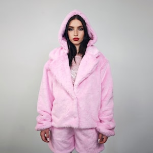 May include: A pink faux fur jacket and matching shorts set with a hood. The jacket has a button closure and a large collar.