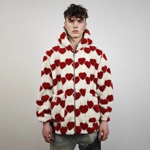 May include: A hooded jacket with a cream-colored background and a pattern of red hearts. The jacket has a zipper closure, two front pockets, and a soft, textured appearance. The jacket is a cozy outerwear option.