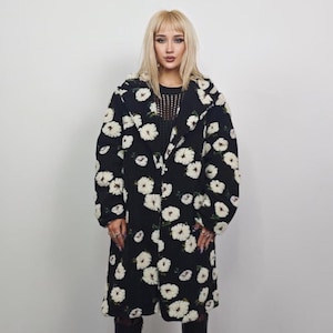 May include: A black coat with a white floral pattern. The coat is long and has a classic lapel design. The white flowers are scattered across the coat, creating a striking contrast against the black background. The coat is a stylish outerwear piece.