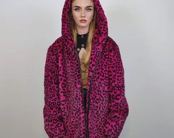 May include: A hooded jacket with a vibrant pink leopard print. The jacket features a full zipper and a cozy, oversized fit. The bold pattern and bright color make a statement. The jacket is a stylish outerwear piece.